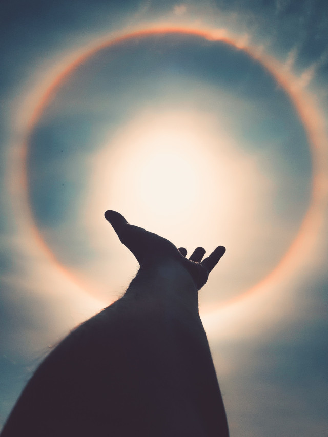A hand gesturing towards thte sun
